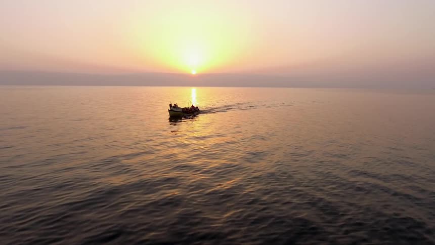 A boat is moving in the water at sunset