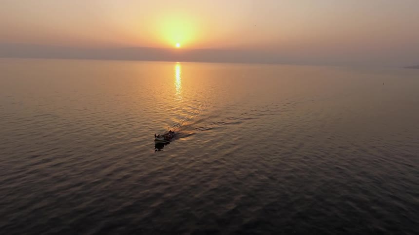 A speedboat travels through the water at sunrise