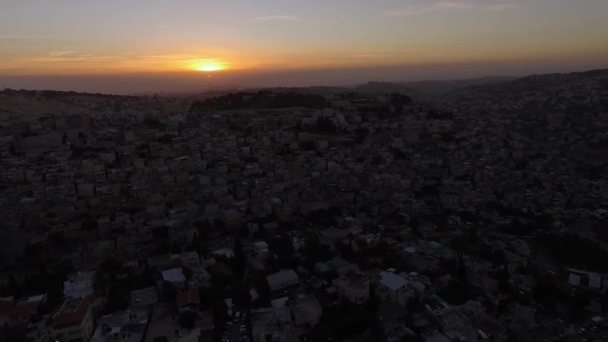 Cluster of buildings in a city with sunset in the distance