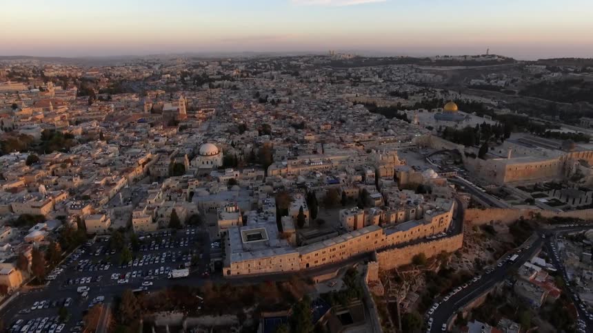A city lies on a plain with a large fortress like structure in the foreground