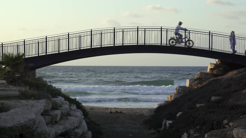 A bicyclist rides over a bridge on the beach