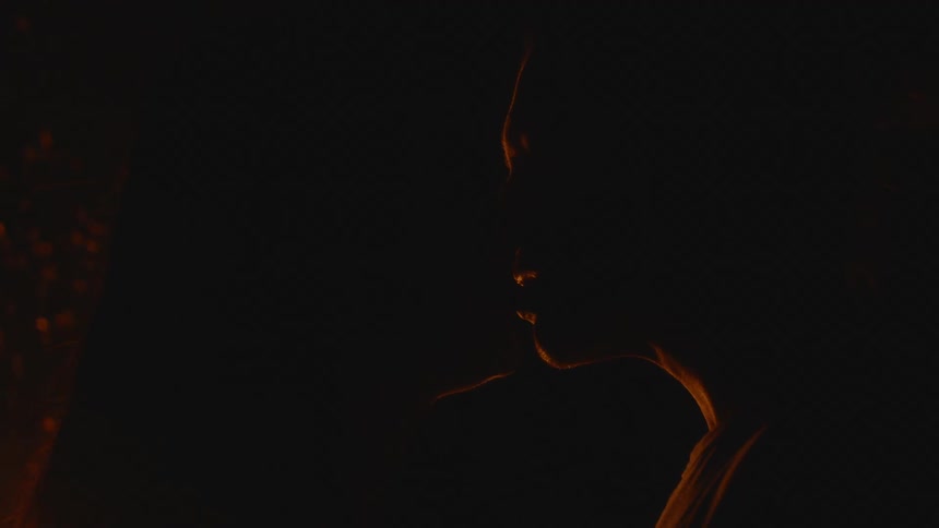 Silhouette of a couple in front of a campfire kissing romantically during the night