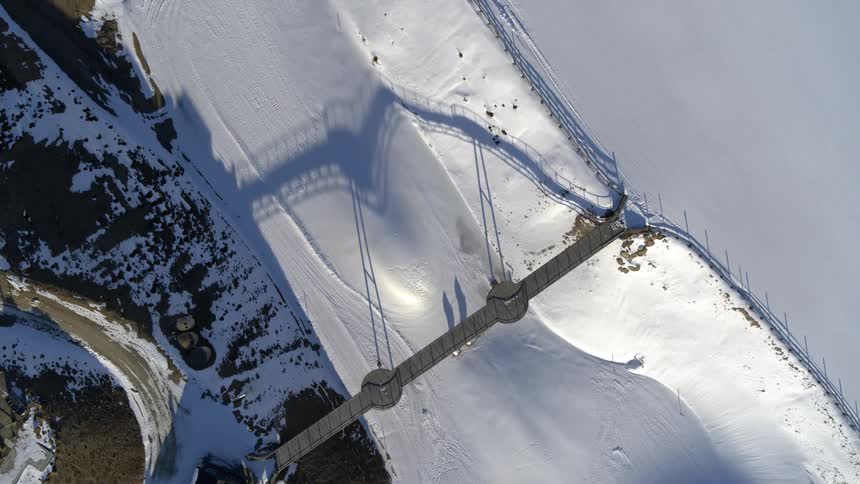 Aerial view of a bridge crossing over a valley covered in snow