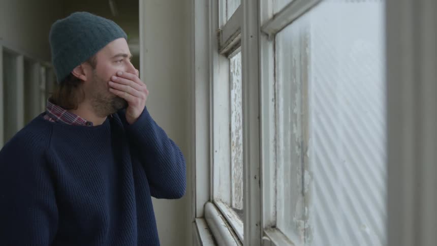 A man smokes his vape and coughs