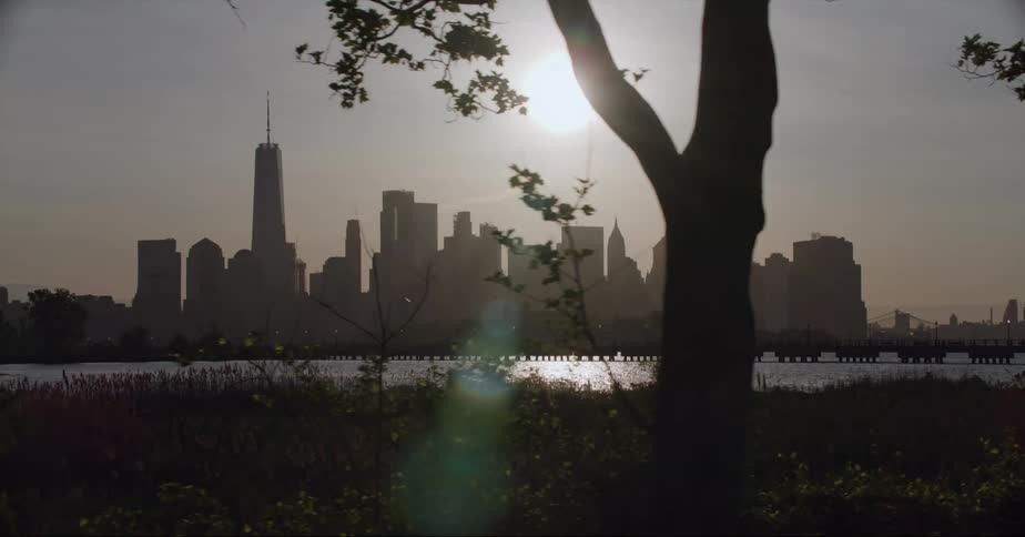 City skyline with high rise buildings and skyscraper is silhouetted against the sun