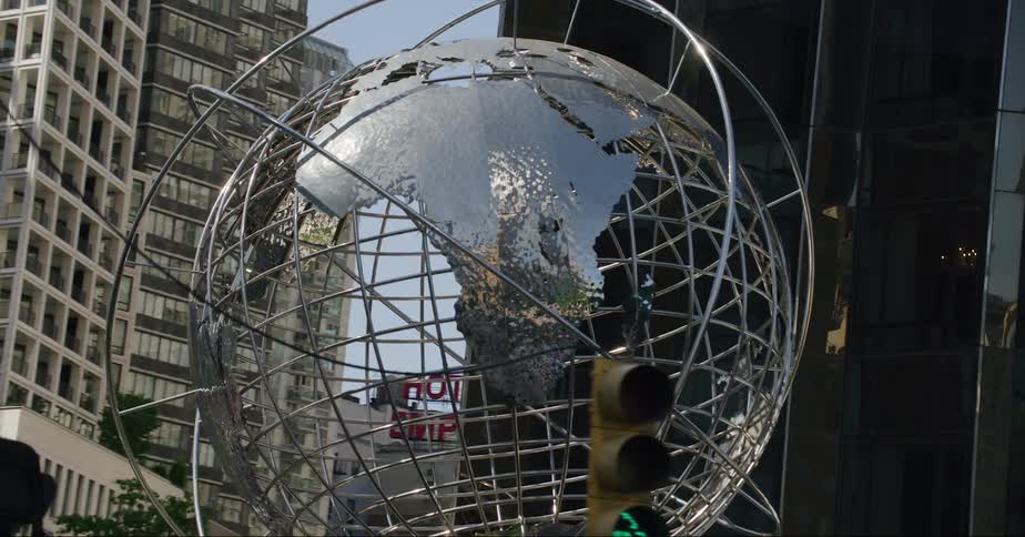 Metal sculpture of the globe stands ata downtown street corner near the base of a building