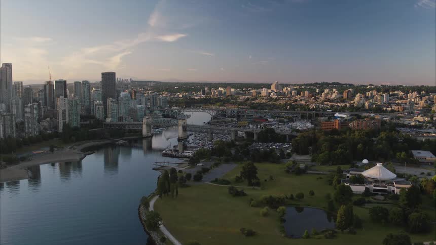 Aerial view of bridge over river between park and high rise buildings in Vancouver city at sunrise