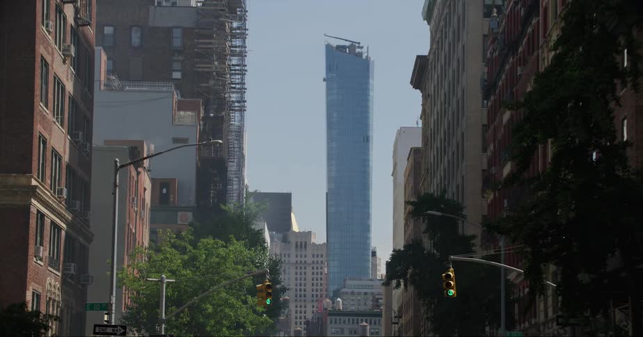 Vehicle drives on street with apartment buildings and skyscraper in the city