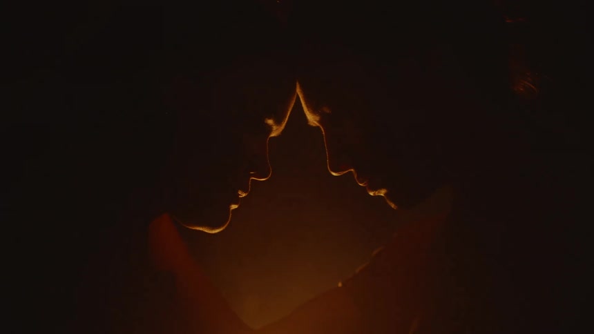 Couple standing in front of a campfire touching heads against each other in a romantic way