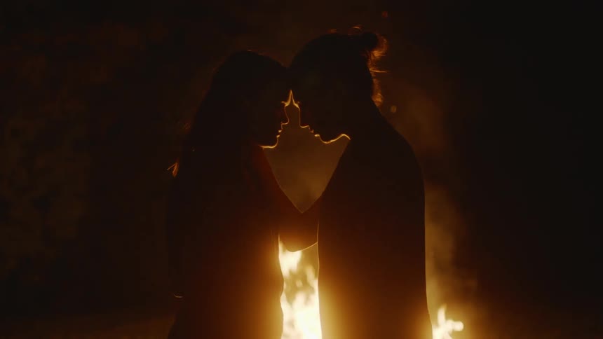A couple is standing head to head in front of a fire