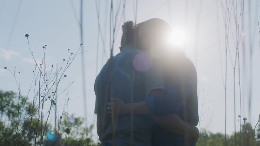 Loving couple hugging each other while standing in the nature at a sunny day