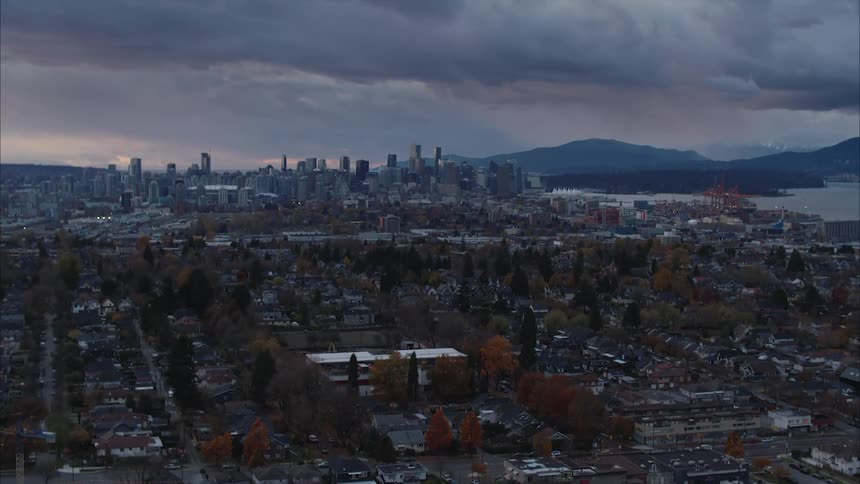 Sprawling city of Vancouver can be seen beneath a stormy gray sky and nearby coast mountains