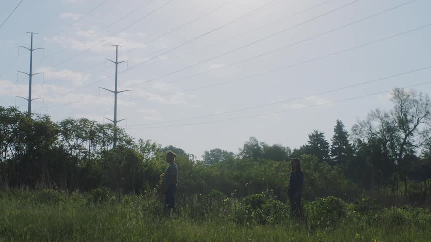 Two people standing in the grass frozen and unmoving
