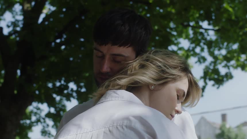 Couple stading outdoors during daytime hugging each other with closed eyes