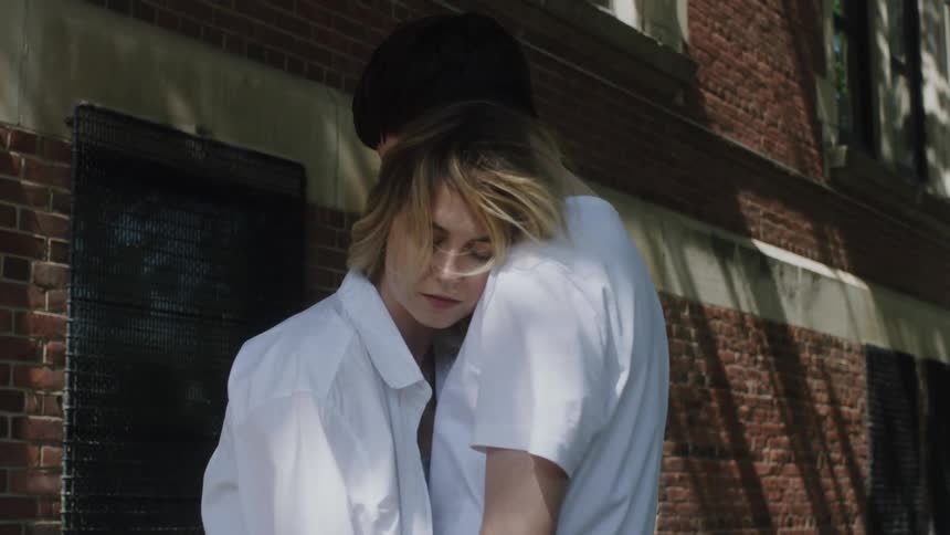Young couple standing in the sidewalk hugging in front of a building in the city