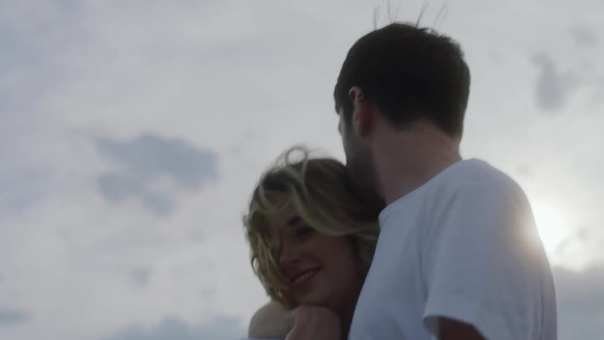 Man wrapping his arms around his girlfriend and kissing her head while theyre walking together
