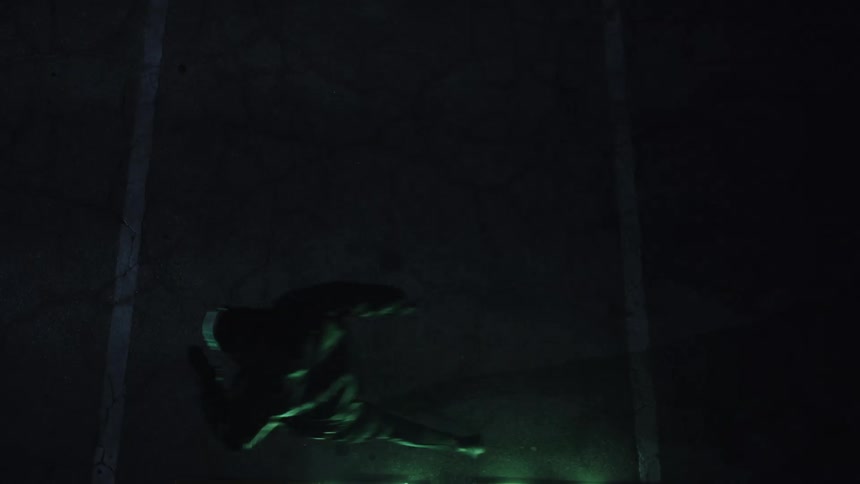 Person wearing mask and hood runs across parking spaces at night