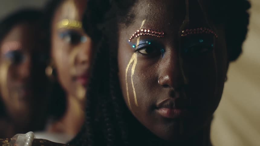 Close up of the faces of a group of African American women with decorative paint and makeup