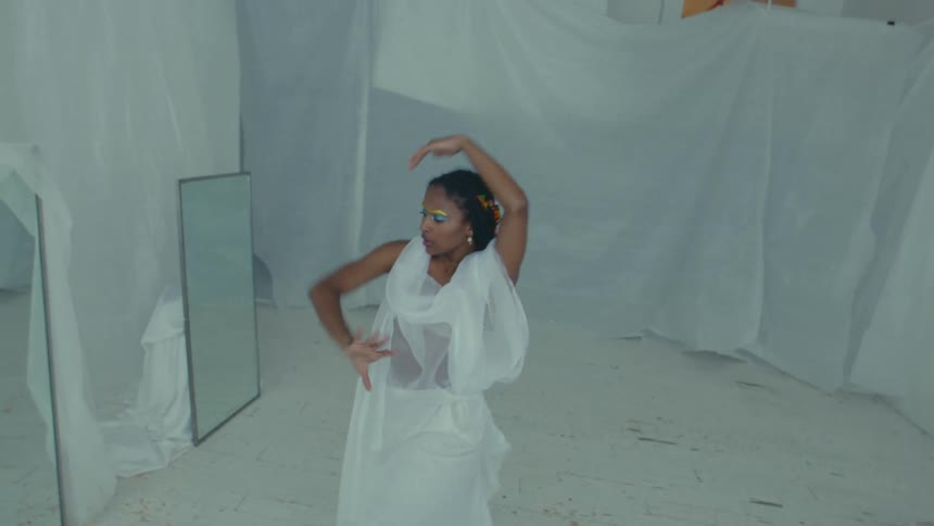 Female dancer dances among mirrors in room draped with white fabric
