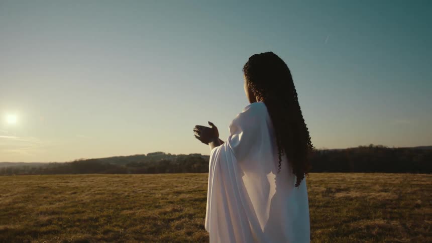 A woman is stretching and doing martial arts moves outside in a field