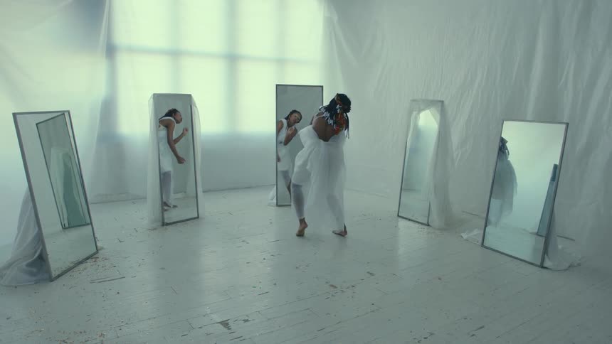 A woman dances in front of mirrors