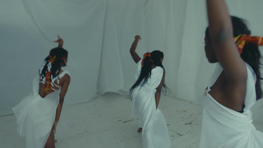 Group of women wearing white dresses dancing on a room surrounded by mirrors