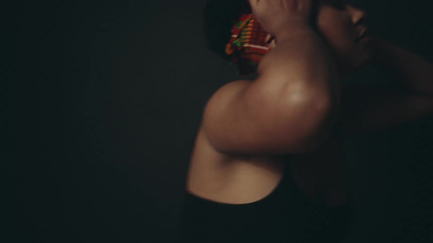 Black woman wearing a headband dancing in a black studio