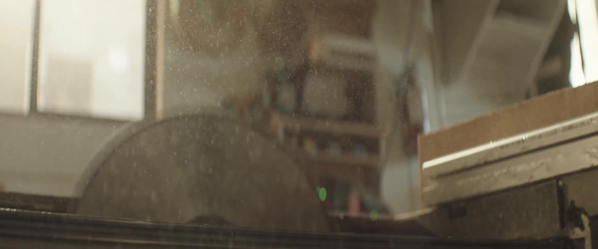 A sawblade is kicking up dust in a workshop