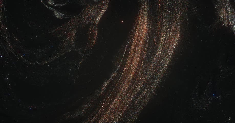 In the darkness a liquid with glittering particles suspended in it spreads