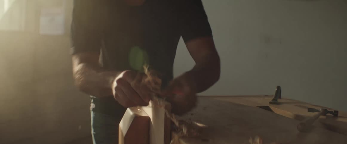 A man is at a workshop using a vice and planer on a piece of wood