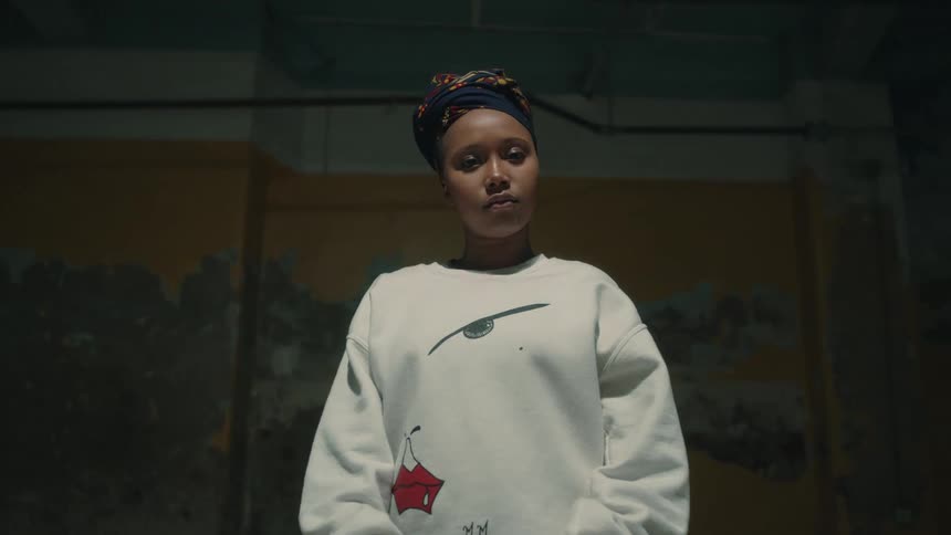 A portrait of a black woman standing in an industrial warehouse space