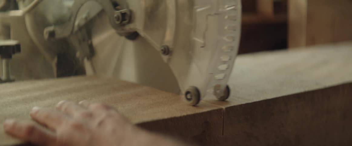 Man uses a circular saw inside a workshop to cut a wooden board in half