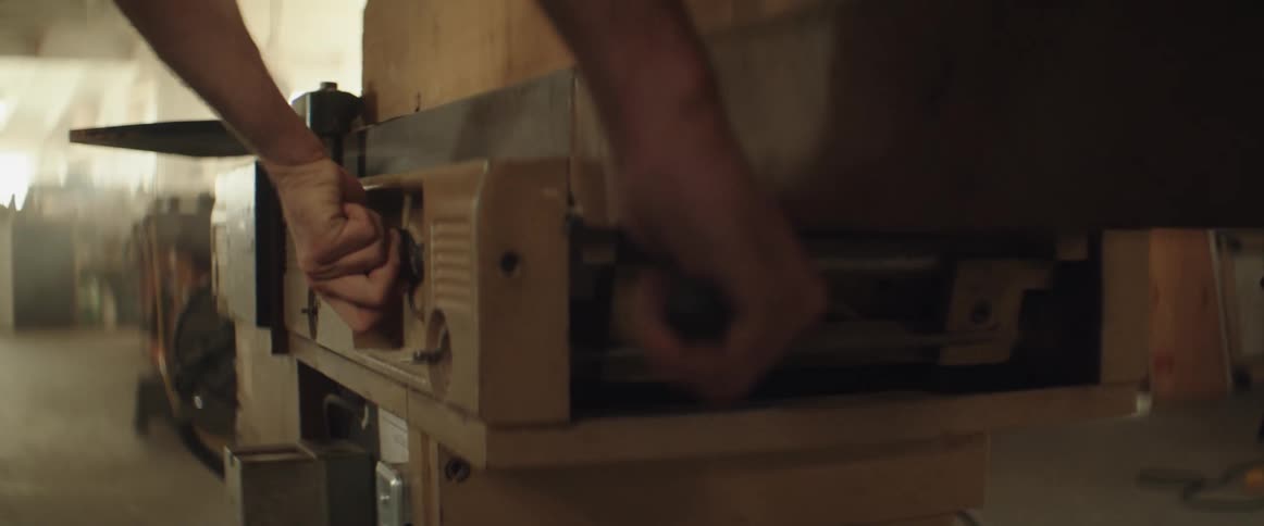 A man adjusts knobs on a machine in a shop