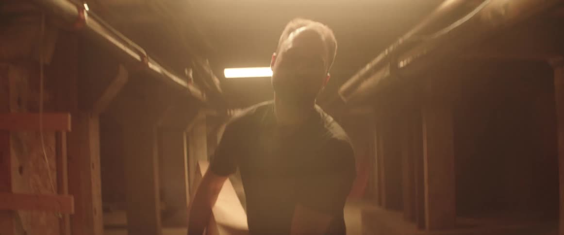 A man carrying a piece of wood down a hallway
