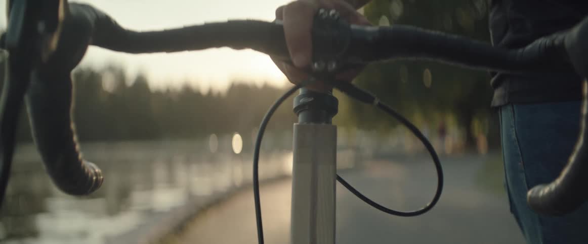Man pushes a bicycle close to a body of water at sunset