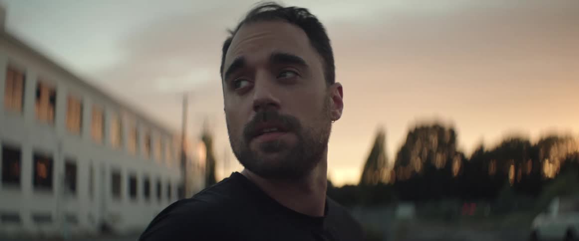 Hispanic man standing outdoors at sunset looking around while turning his head back