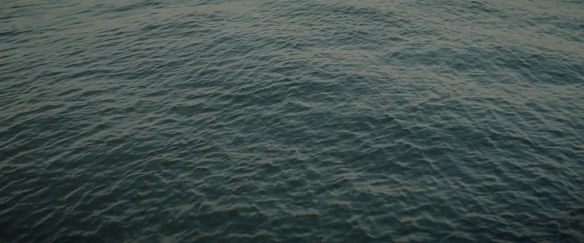 Body of calm sea water gently ripples in the fading sunlight