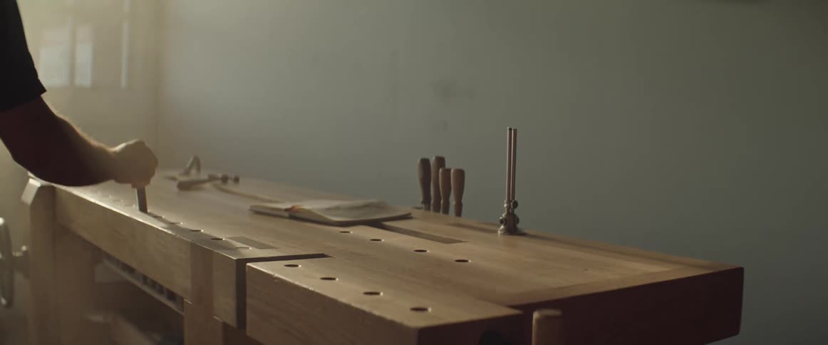 A woodworker works on a table in his workshop