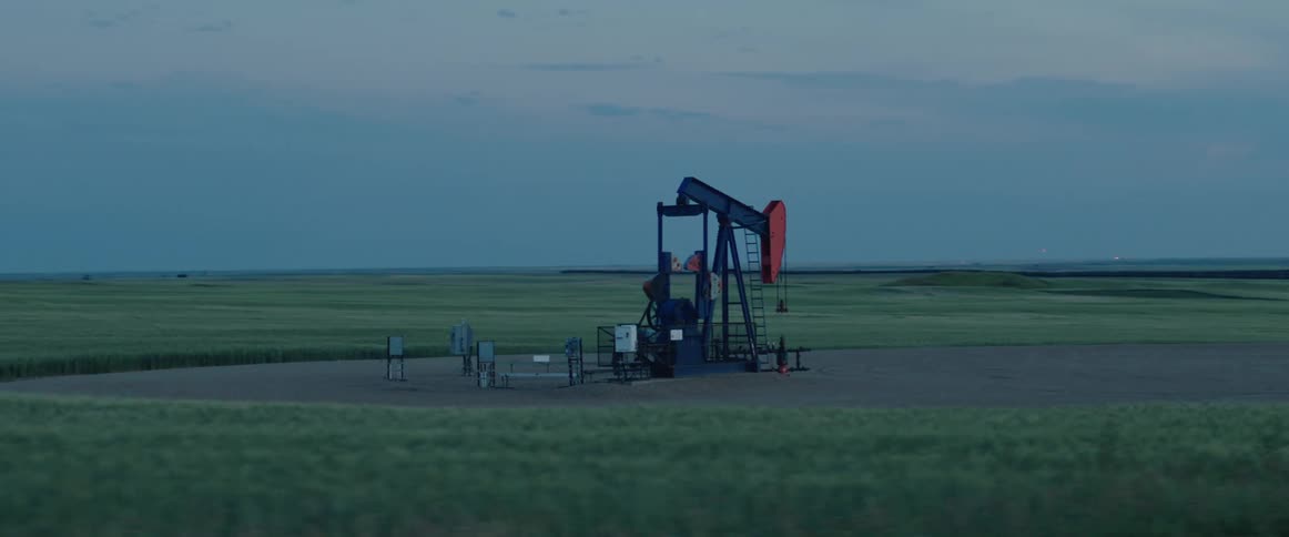 Solitary pump working on an oilfield in the countryside at evening