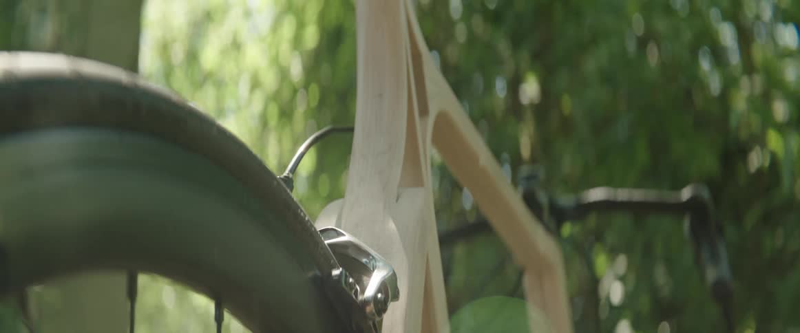 Close up of wooden bicycle against trees swaying in the wind