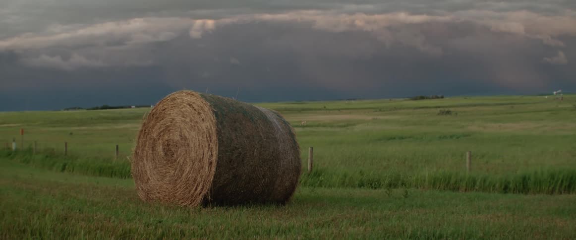 Dark storm clouds over a field with a hay bale