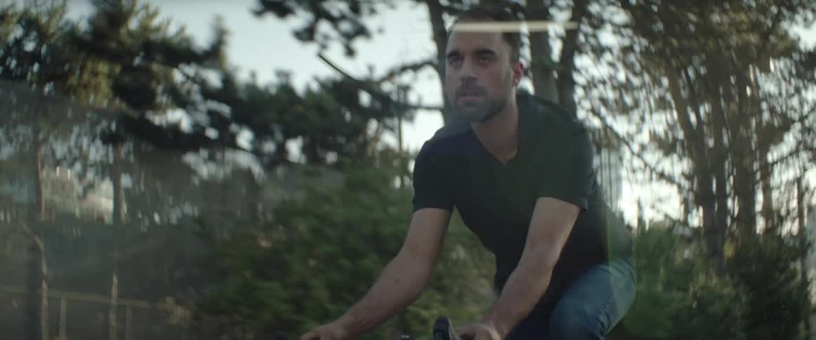 Man in jeans riding a bike down the streets of a suburban area