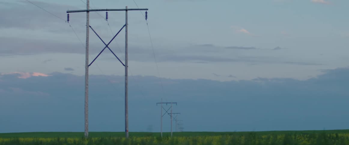 View of power lines in a field at dusk