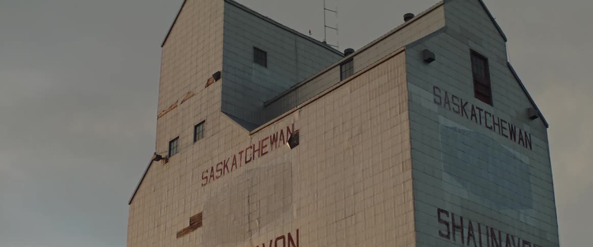A tall grain elevator with only a few windows has words painted on it