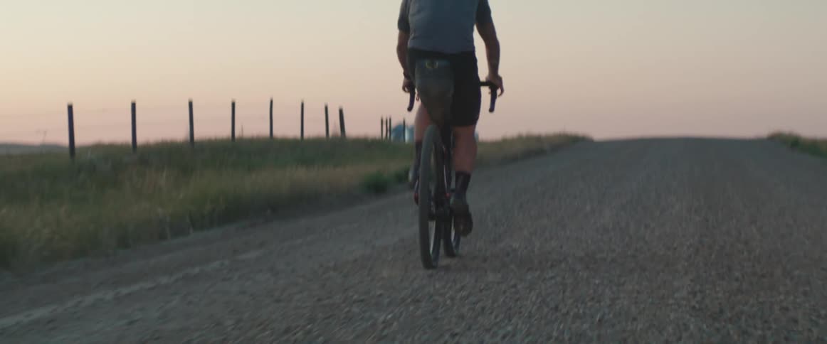 Man wearing a helmet riding his bike on the road in the countryside at dusk
