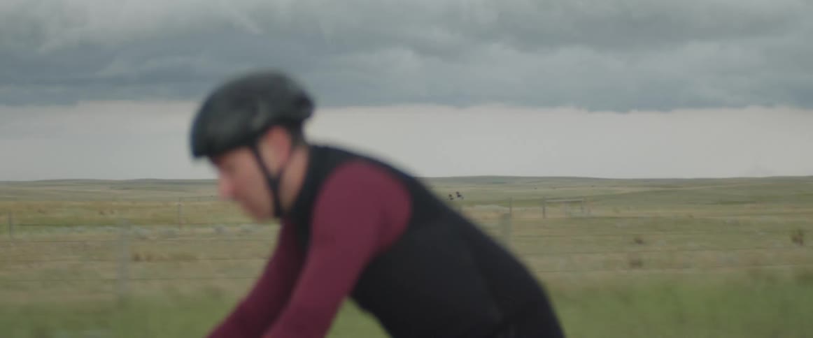 Focused man wearing a safety helmet riding his bike by an open grass field