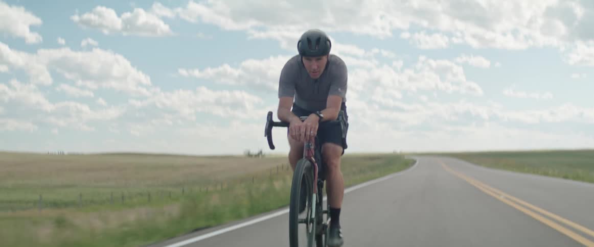 A man riding a bicycle outdoors on a paved country road