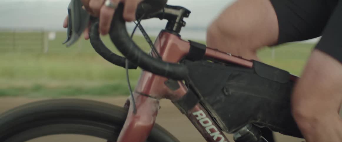 Man wearing shorts riding his red bike across a dirt road