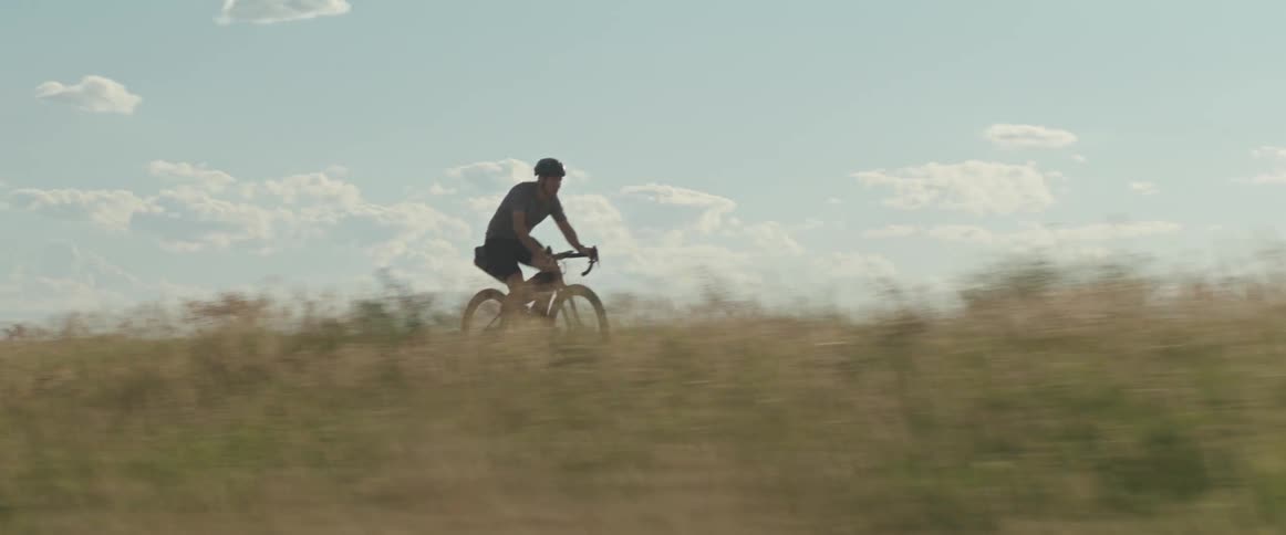 Male cyclist rides on elevated country road in the afternoon