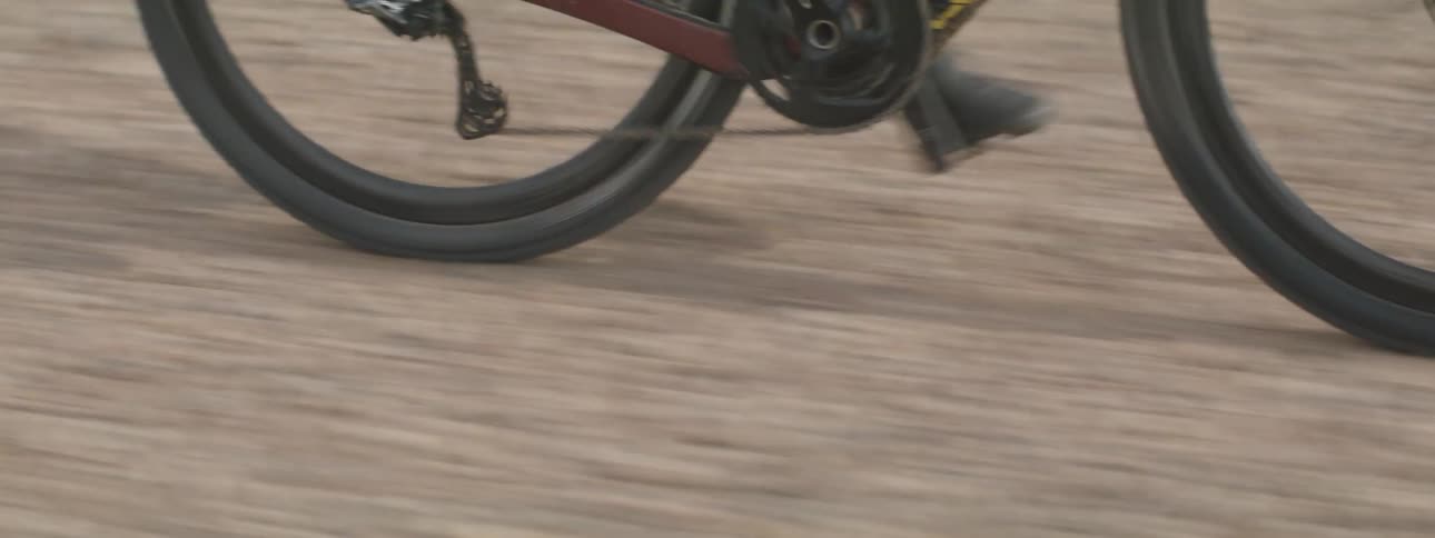 Tires of a gravel bicycle travel across the dirt road